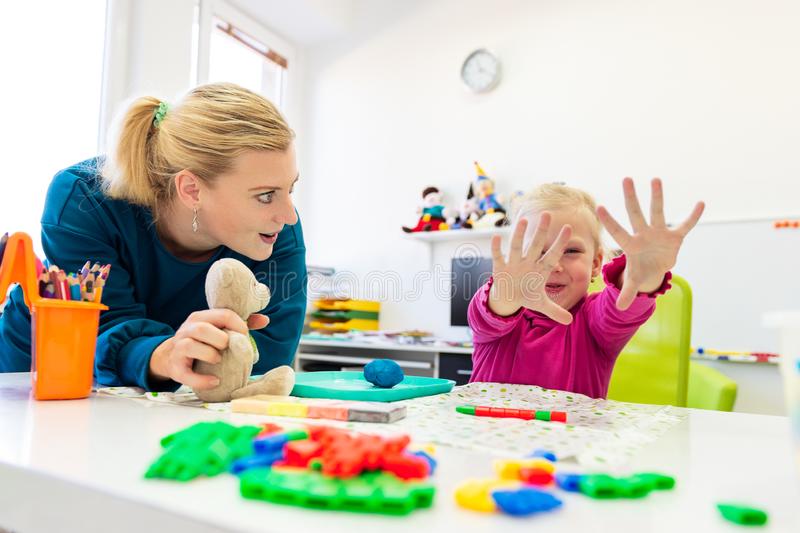 niña pequeña en sesión de terapia ocupacional infantil haciendo ejercicios sensoriales juego con su terapeuta 160355101